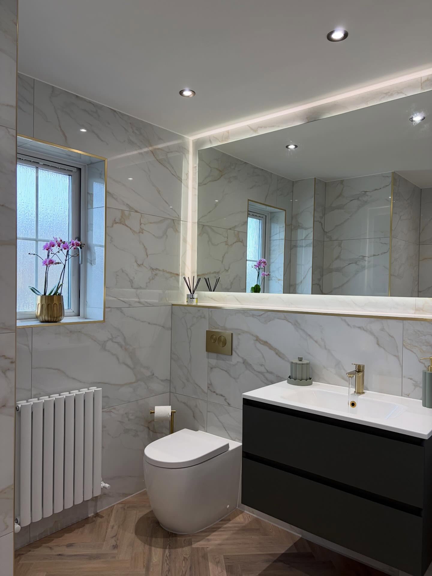 White marble bathroom with LED mirror and dark vanity, fitted by CDM