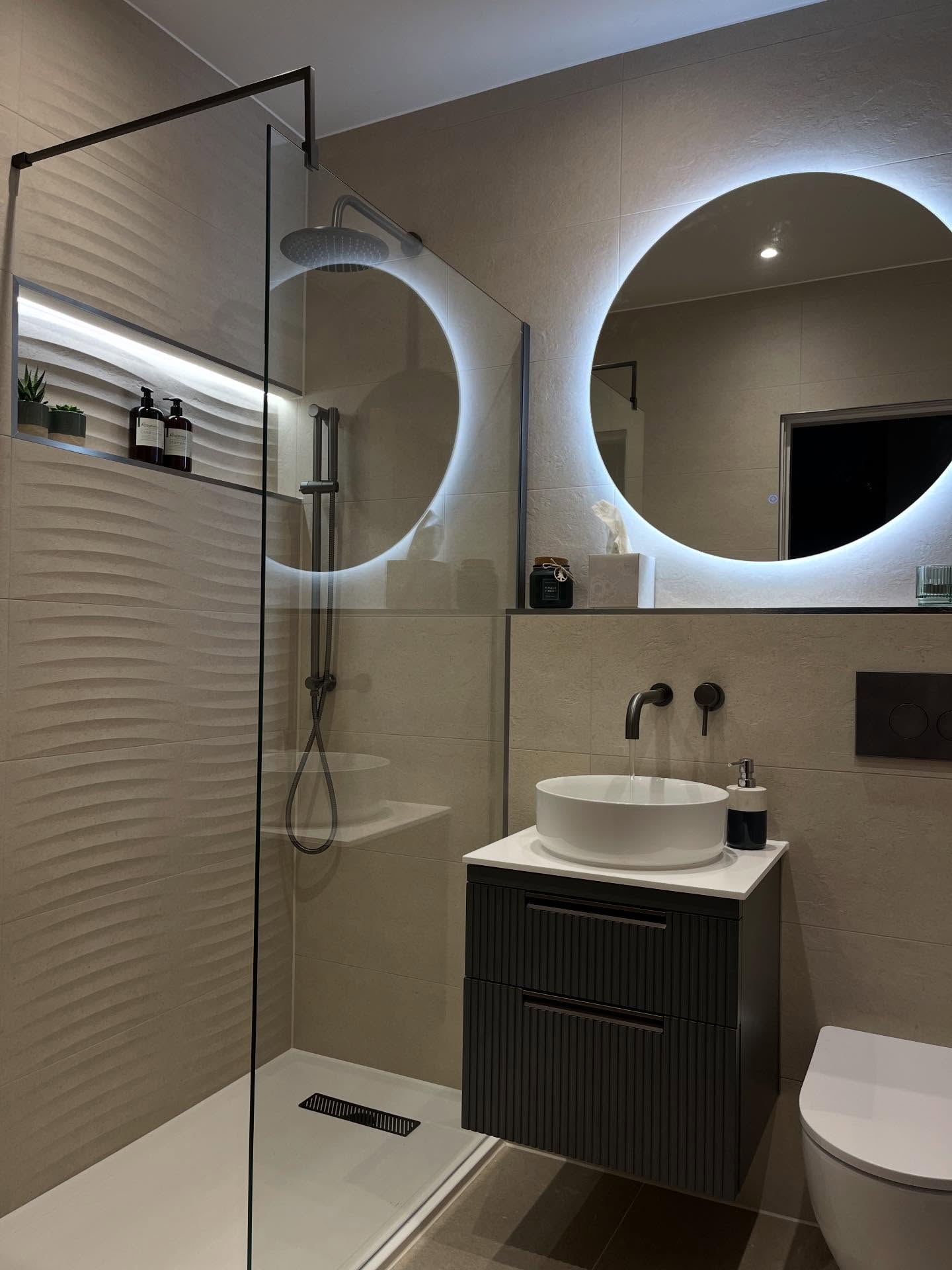 Walk-in shower with textured tiles and twin backlit mirrors, fitted by CDM