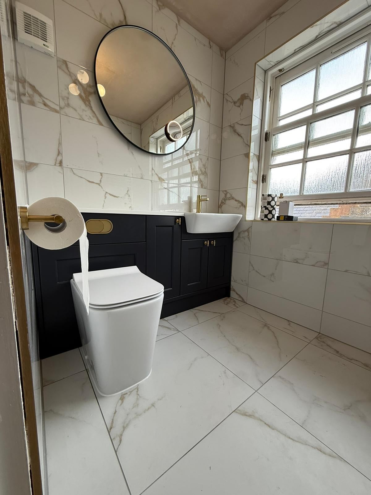 Navy vanity bathroom with marble tiles and brass fittings, fitted by CDM
