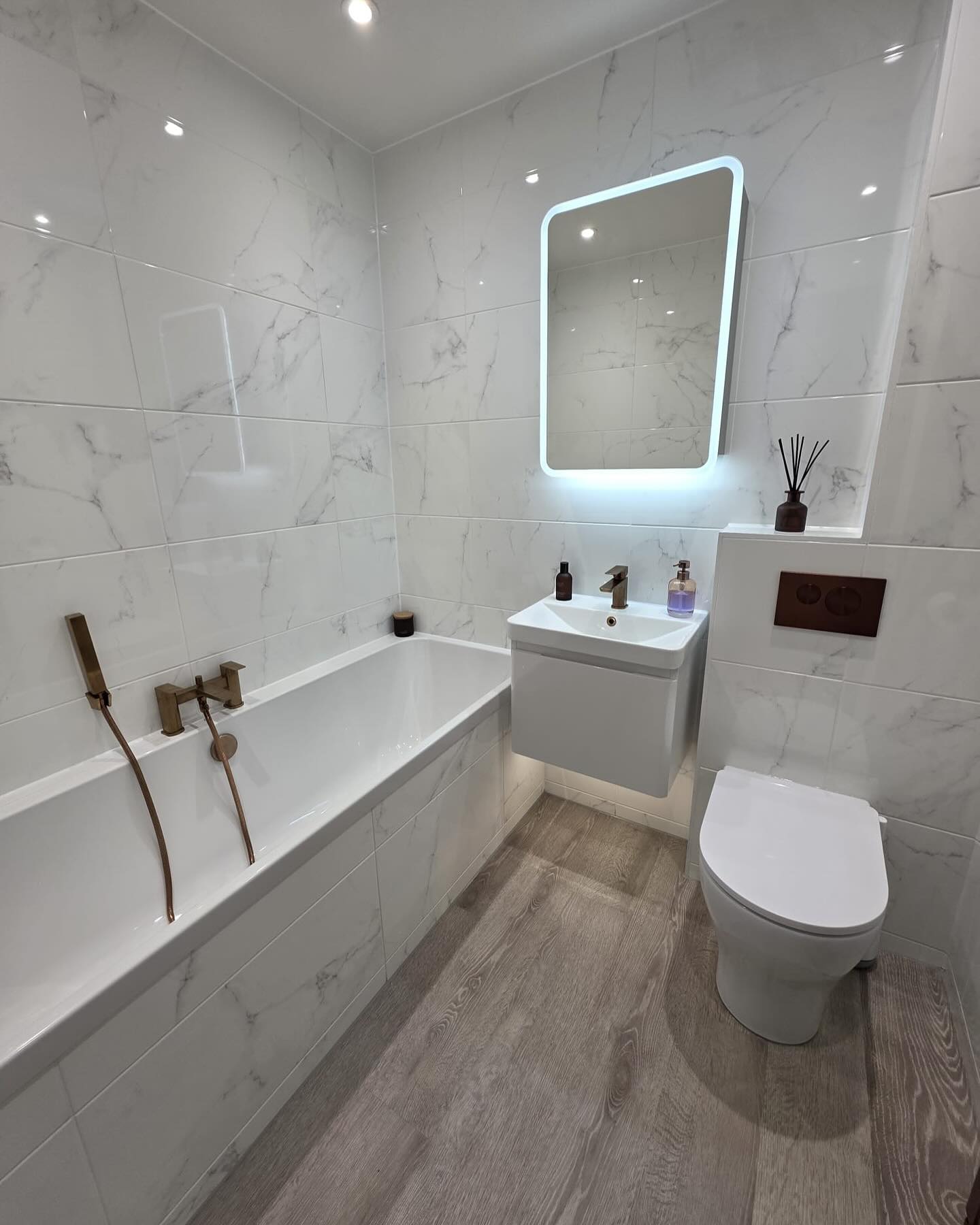 Marble bathroom with copper fittings and wood-effect flooring, fitted by CDM